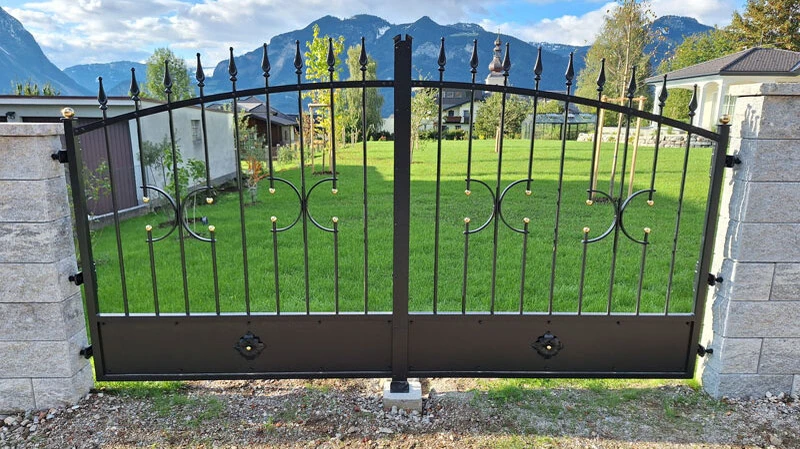 Handgeschmiedetes Doppelflügeltor in modern-klassischem Design – gefertigt aus massivem Stahl mit elegant geschwungenen Linien, kunstvollen Schmiededetails und dekorativen Spitzen.