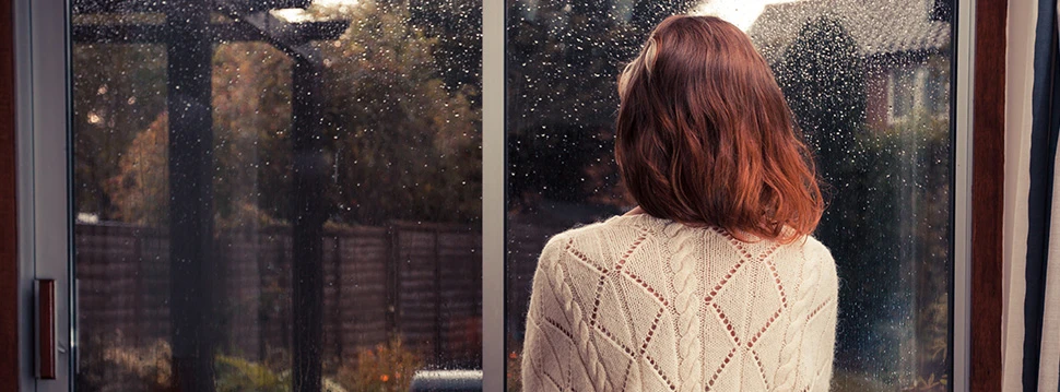 Frau schaut aus dem Fenster bei Regen