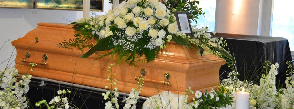 Holzsarg mit weißen Blumenarrangements in einem stilvoll dekorierten Raum