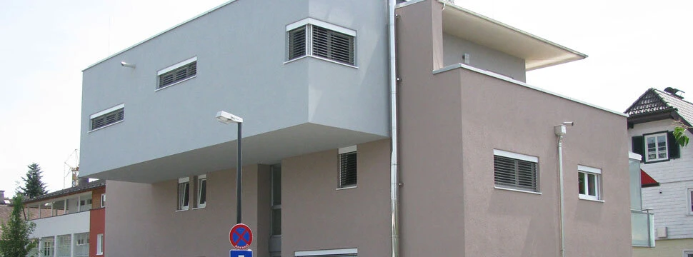 Modernes Wohnhaus mit kubistischer Architektur, Flachdach und Carport in städtischer Umgebung.