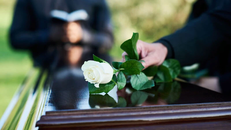 Eine weiße Rose auf dem Sarg steht für Reinheit und ist eine stille Geste des Abschieds bei der Trauerfeier.