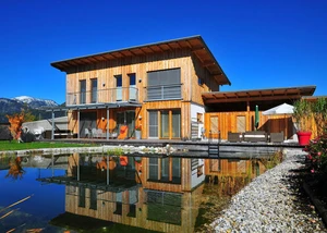 Modernes Wohnen im Einklang mit der Natur – ein Holzhaus mit klarer Architektur, großzügiger Terrasse und Schwimmteich zeigt, wie nachhaltiges Bauen und hoher Wohnkomfort zusammenfinden.