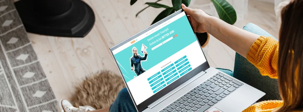 Eine junge Frau sitzt mit ihrem Laptop auf einer Couch und sucht auf better-jobs.at nach einem passenden Jobangebot.