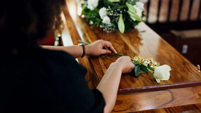 Bestattungsvorsorge in Schladming und Gröbming | Frau legt weiße Rose auf Sarg