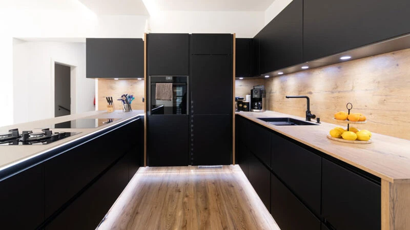 Schwarze Küche mit Holzelementen von Reparaturtischlerei Schinnerl