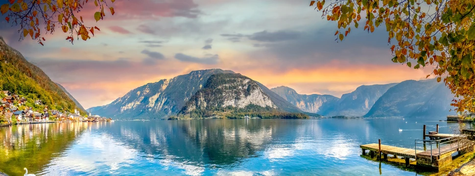 Blick auf den Hallstätter See im Salzkammergut in Österreich, abendliche Stimmung, rechts ist Hallstatt zu sehen, rechts Bäume und ein Steeg