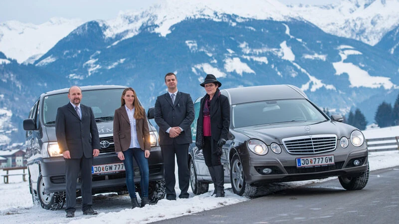 Team von Bestattung Wimmer mit Fahrzeugen vor Schneelandschaft und Bergen im Pongau.